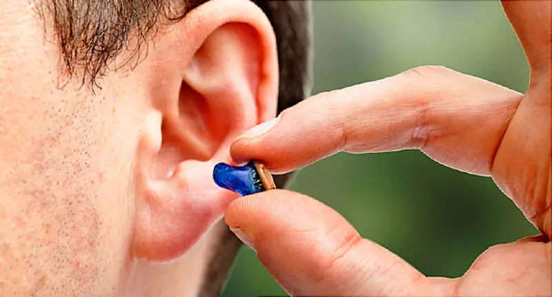 Tiny invisible hearing aid next to fingertip